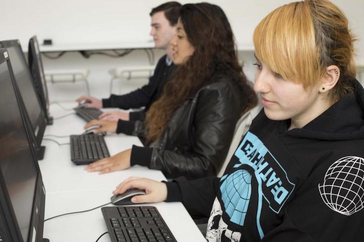 three students sitting at computers in a on campus computer lab